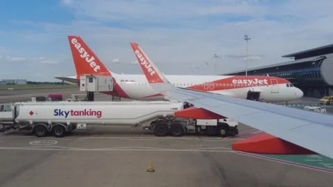 The panning shot from the wing view shows an EasyJet plane parked at Brussels Stock Footage 280840781