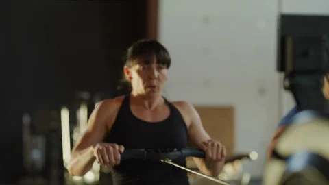 Panning shot of woman using rowing machine in gymnasium / Lehi, Utah, United Stock Footage 94429976