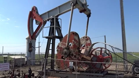Panning shot of working oil pumpjack and flywheel in rural landscape Stock Footage 335375198