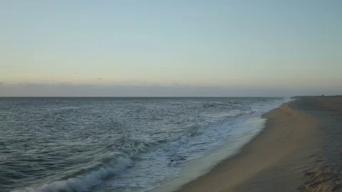 Panning the sunrise from the beach to the rocks Stock Footage 98743353
