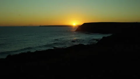 Panning sunset over the ocean coast of Australia with a silhouette of cliffs Stock Footage 317926138