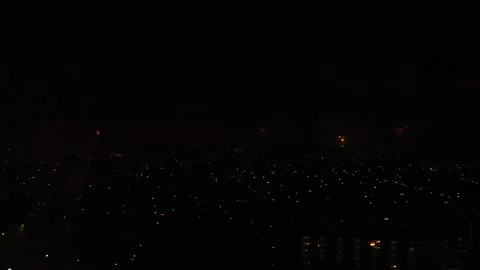 Panning Through Cityscape At Night With Exploding Fireworks On Dark Sky. Stock Footage 168695811