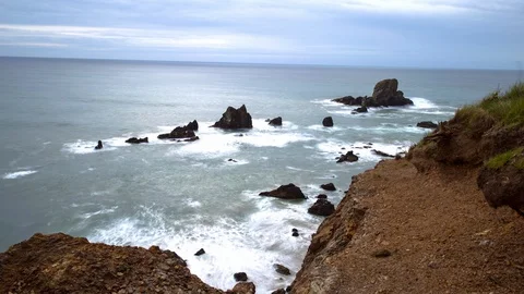 Panning time lapse shot of waves splashing on coastline against cloudy sky - Stock Footage 130069148