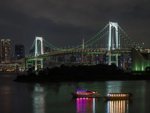 Panning timelapse footage of boats and Rainbow bridge lighted at night Stock Footage