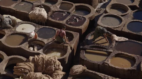 Panning top down shot of tannery leather workers dyeing leather in Fes Stock Footage 265500995