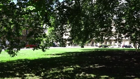 Panning under leaf heavy oak tree to a Bath Terrace England Stock Footage 138210213