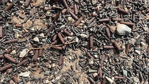 Panning video of spent bullet shells on the ground. Video stock 288371172