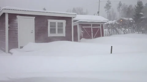 Panning video on strong blizzard - small swedish red wooden cabin Stock Footage 229614679