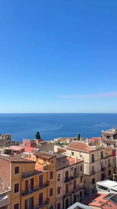 Panning view of coastal town rooftops with ocean backdrop under clear blue sk Stock Footage 346622456