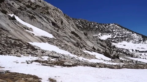 Panning view of granite mountains, snow fields, and an alpine lake Stockbeeldmateriaal 121503753