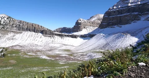 Panning the view to the left of a meadow with snowy views of the summit of Mount Stock Footage 120150678