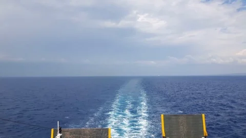 Panning view of moving ferry aft stern and Greek partially torn flag Stock Footage 94021786