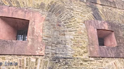 Panning view of an old stone fortress wall with barred windows and the insc.. Stock Footage 346654160