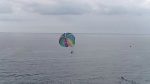 A panning view of people parasailing over a beautiful calm ocean on a Stockbeeldmateriaal 147164791