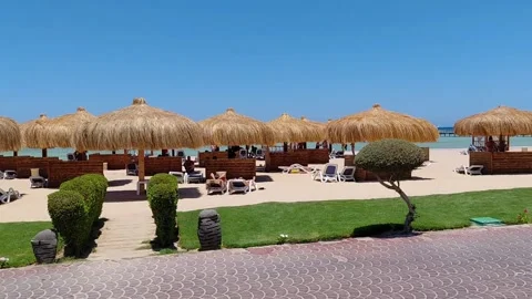 Panning view of sandy resort beach with straw umbrellas in Sahl Hasheesh. Stock Footage 337533376