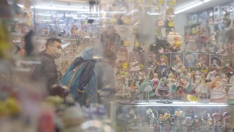Panning view through glass display window to comic book store geek teens Stock Footage 107523361