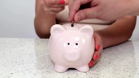 Panning view of unrecognizable person putting coins into a piggybank investme Stock Footage 265936204