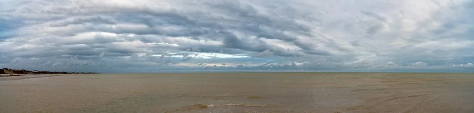 Pano- dramatic clouds float on the coast of the blue sea Stock Photos