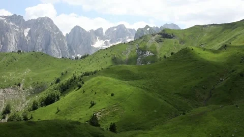 Panorama of alpine meadows with rocky mountains in the background in sunny day. Stock Footage 245345037