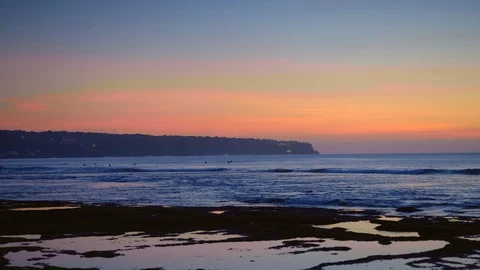 Panorama of a beach after sunset with surfers are swimming in dark blue water Stock Footage 114820344