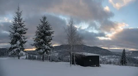 Panorama of Black modern tiny cabin on snowy Carpathian mountains in Ukraine Stock Photos