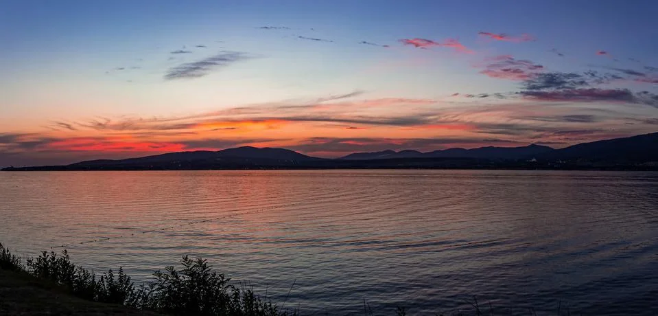 Panorama of a contrasting summer sea sunset over the mountains Stock Photos