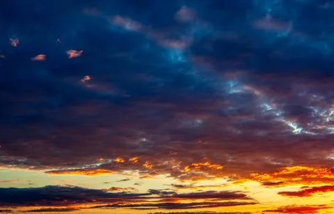 Panorama of the evening sky with dramatic orange, purple and dark blue clouds Stock Photos