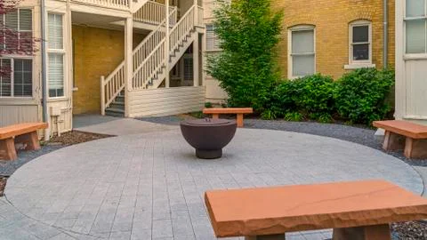 Panorama frame Fire pit on circular pavement with stone benches against building Foto stock