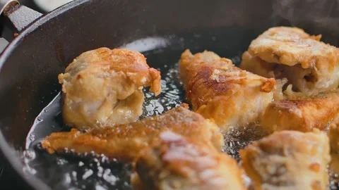 Panorama of a frying pan in which ruddy pieces of white fish are being cooked Video stock 303423949