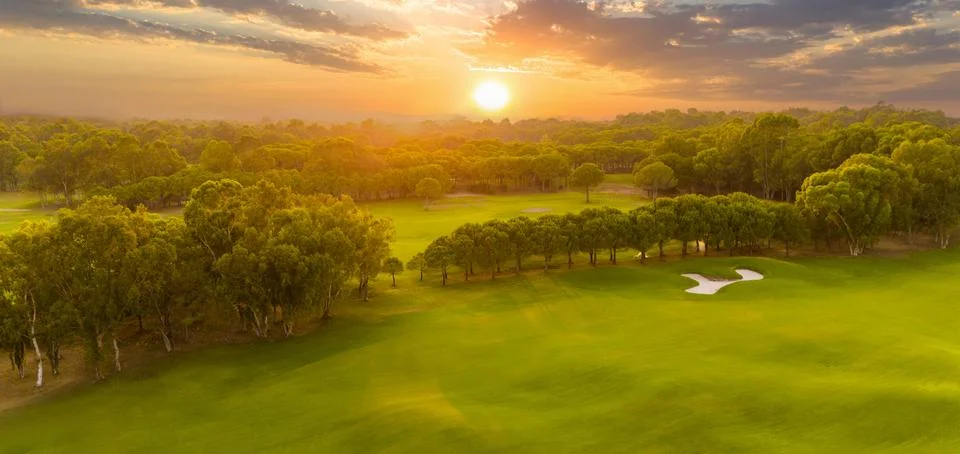 Panorama of golf course at sunset with dramatic sky. Scenic panoramic view of Stock Photos
