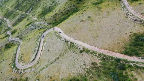 Panorama of the mountain range. A column of ATVs descends the mountain Stock Footage 163503267