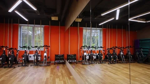 Panorama with reflection of bicycle trainers in gym and other training equipment Stock Footage 276367449