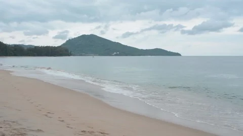 Panorama of sandy beach with waves. Against mountains. Video stock 85692300