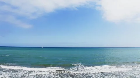 Panorama of the sea with small waves and a sailboat visible in the distance. Stock Footage 302080923