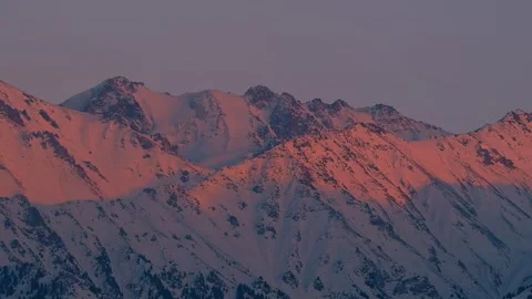 Panorama of snow-capped mountains illuminated by the pink light of sunset Stock Footage 321892449