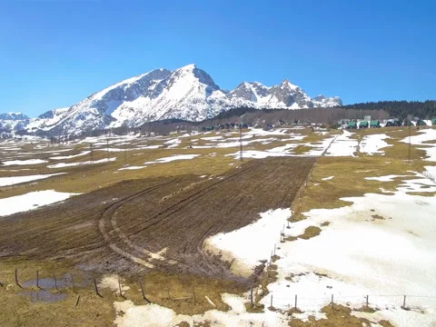 Panorama of spring field and  snow-capped mountain aerial view Stock-Footage 77034079