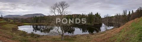 Panorama of trees in autumn colours reflecting in Tarn Hows, Lake District Stock Photos