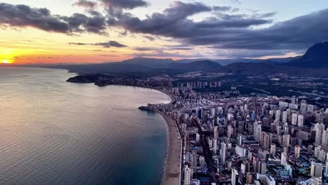 Panoramic aerial capture of sunset over coastal cityscape with beachfront and Stock Footage 342360975