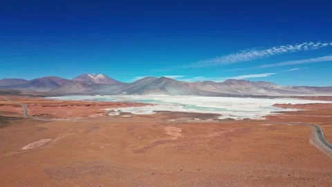 Panoramic aerial over vast red desert plain showcasing iconic turquoise lagoon Stock Footage 335975170