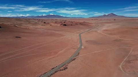 Panoramic aerial shot of empty desert road cutting through vast red arid plain Stock Footage 334976878