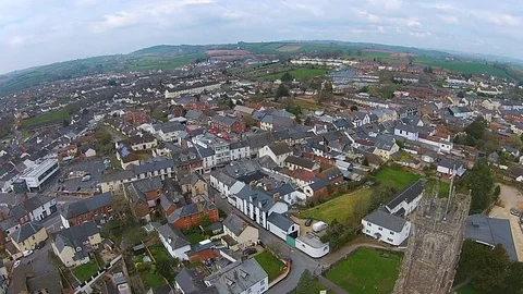 Panoramic aerial view above buildings, roads &amp; fields in a suburban UK town Stock Footage 80288552