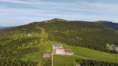 Panoramic aerial view of alpine lodge cluster on forested ridge with green Stock Footage 345286562
