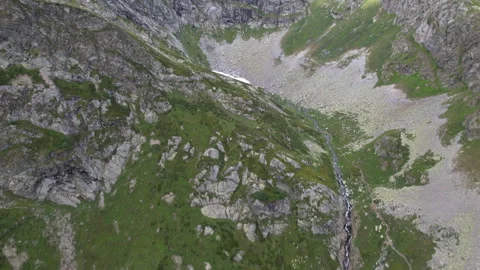 Panoramic aerial view of a mountain stream flowing from a glacier. Vidéo 260793765