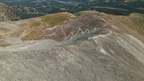 Panoramic bird's eye view above truck and dirt road with switchbacks on Stock Footage 287364343