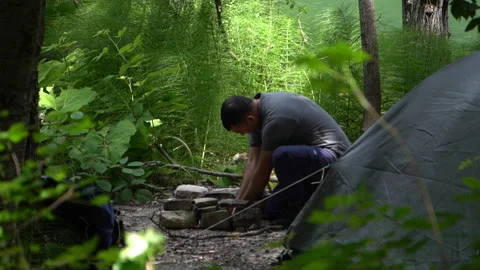 Panoramic Camera View of Hiker Starting a Campfire Beside Tent by a Lake Stock Footage 312763833