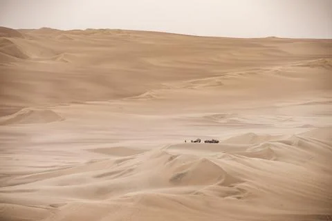 Panoramic desert dunes with distant vehicles and people, travel in Peru Stock Photos