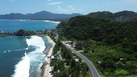 Panoramic drone shot of a seaside harbor, sandy beach, and scenic coastal road 库存照片