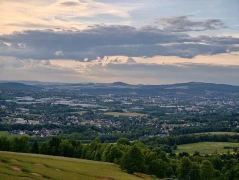 Panoramic green valley with distant town beneath dramatic evening sky Foto stock