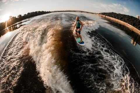 Panoramic high angle view of man in turquoise life jacket riding wave on Stock-Fotos