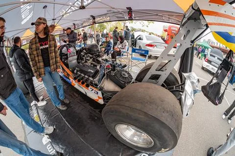 A panoramic image showcasing a parked racing car off-track, possibly at a m.. Stock Photos
